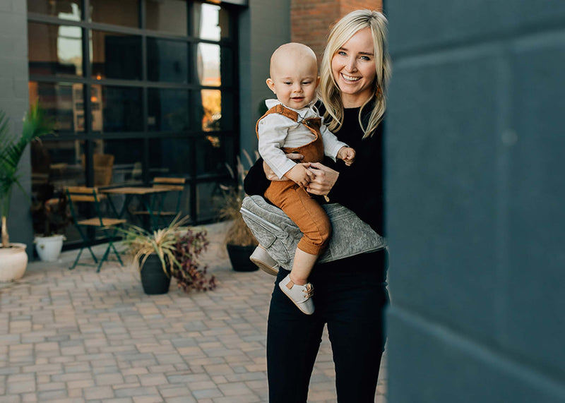 a mother carrying a toddler on tushbaby hip carrier