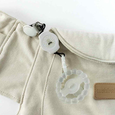 Llama Retractable Pacifier Clip attached to a Cream Tushbaby Hip Carrier and a clear pacifier