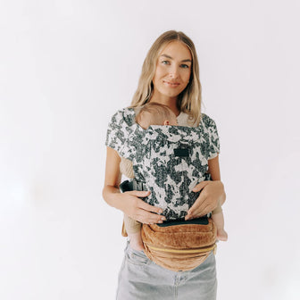 Adult carrying a sleeping baby facing inward in an Abstract Hip Seat Hands-Free Attachment with a Velvet Sable Tushbaby Hip Carrier