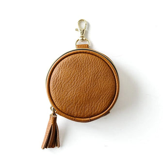 The Pod in Cognac with pebbled texture, a gold-tone clip, and tassel zipper pull on a white background