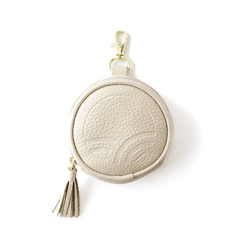 The Pod in Cream with pebbled texture, an embossed logo, gold-tone clip, and tassel zipper pull on a white background