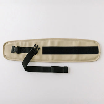 The Waistband Extender in Cream laid flat, showing the adjustable black strap, buckle, and hook-and-loop fastening panel