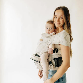 Adult carrying a baby facing outward in a Marble Hip Seat Hands-Free Attachment with a Marble Tushbaby Hip Carrier